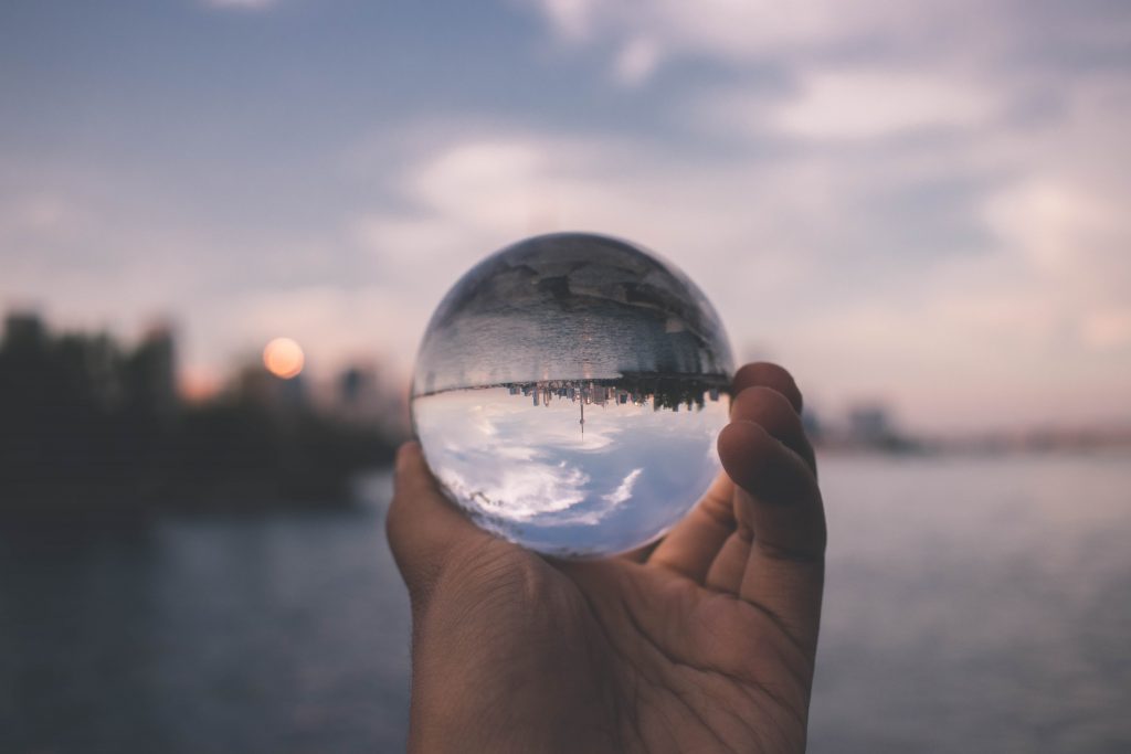 Person holding glass sphere that shows view in distance inverted